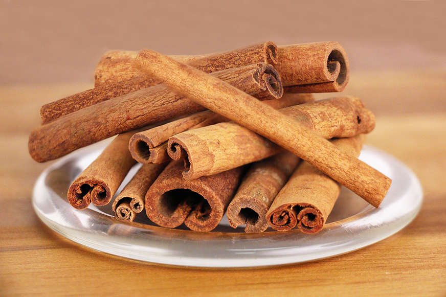 Cinnamon sticks on a white plate with a wooden background